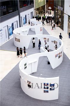 people are walking around in an open area with white walls and circular seating areas on the floor