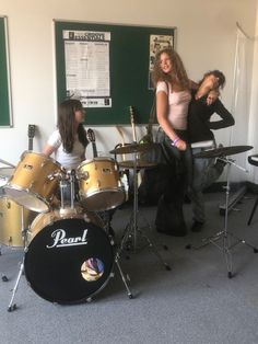 two women and a man are playing drums