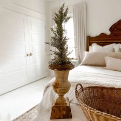 a potted plant sitting on top of a wooden stand in front of a bed