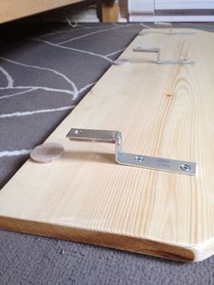 a piece of wood is being sanded down on the floor by a pair of nails