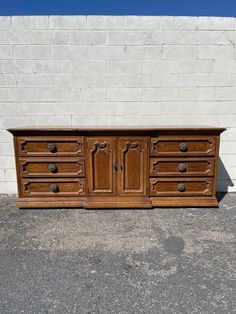 an old wooden dresser sitting in front of a white brick wall with two doors on each side