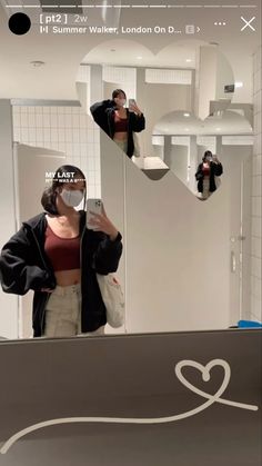 a woman taking a selfie in front of a mirror while wearing a face mask