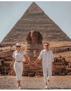 two people holding hands in front of the pyramids