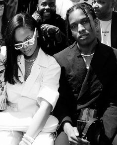 two people sitting next to each other in front of a group of people wearing sunglasses