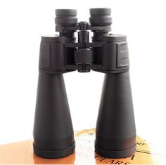 two black binoculars sitting on top of a wooden table