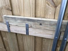 a close up of a wooden fence with metal bars attached to the side and wood planks behind it