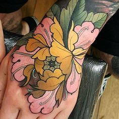 a person's hand with a flower tattoo on it