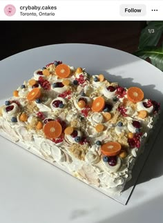 a white plate topped with a cake covered in fruit and veggie toppings