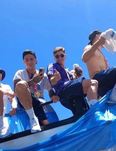 four men sitting on the back of a boat with one man taking a selfie