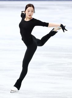 a woman skating on an ice rink wearing a black outfit and holding her arms out