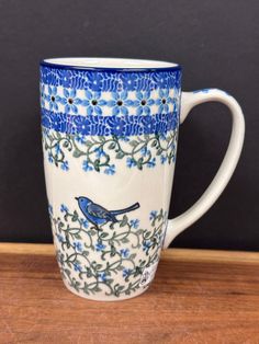 a blue and white coffee cup sitting on top of a wooden table