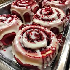 several red velvet rolls with white icing in a pan