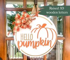 a wooden sign that says hello pumpkin hanging from the front door with a bow on it