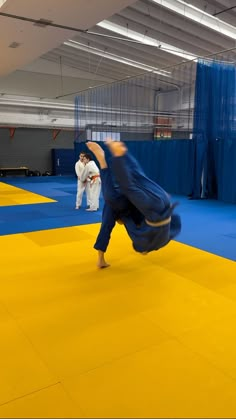 two people doing karate moves in an indoor area with blue mats and yellow flooring