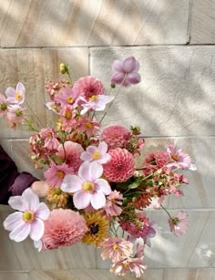 a woman holding a bouquet of pink and yellow flowers