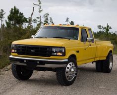 a yellow pick up truck is parked on the gravel