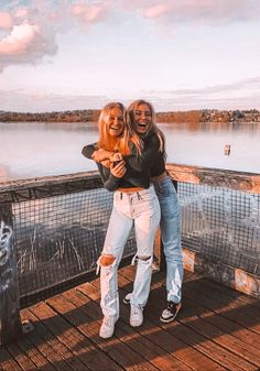 two women are standing on a dock by the water and one has her arms around the other