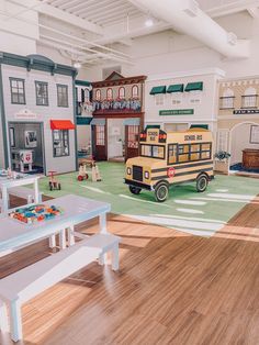 a toy school bus is in the middle of a playroom with tables and benches