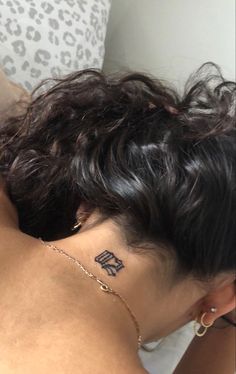 the back of a woman's head with a tattoo on her left side neck