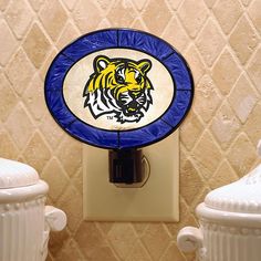 two white urinals are next to a blue and yellow stained glass tiger emblem