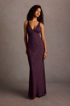 a woman in a long purple dress posing for the camera with her hand on her hip