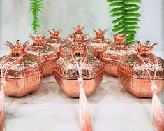 copper pots with tassels are sitting on a table