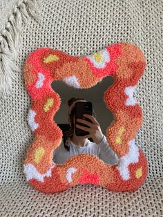 a woman taking a selfie with her cell phone in front of a decorative frame