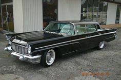 an old black car parked in front of a building