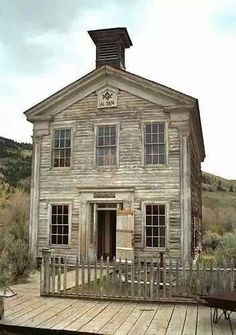 an old wooden house sitting on top of a wooden deck