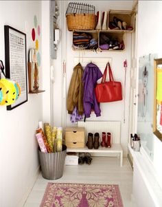 a hallway with shoes, bags and purses hanging on the wall next to a rug