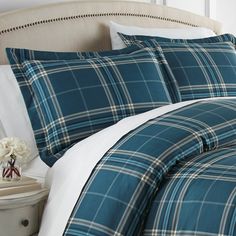 a bed with blue plaid comforter and pillows