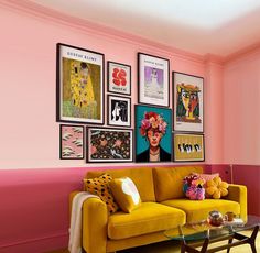 a living room with pink walls and pictures on the wall, including a yellow couch