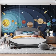 a bedroom with planets on the wall and stuffed animals in the bedding area,