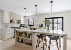 a kitchen with two stools next to an island in the middle of the room