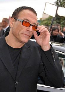 a man wearing sunglasses talking on a cell phone in front of a group of people