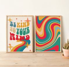 two colorful posters on a wooden shelf next to a potted cacti and cactus