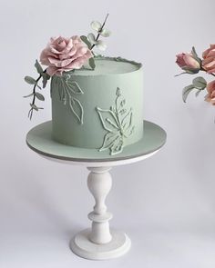 there is a green cake with flowers on the top and bottom, sitting on a white pedestal