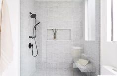 a white tiled bathroom with a shower head and hand held shower faucet in the corner