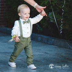 a little boy wearing suspenders and a bow tie holding his hand out to someone