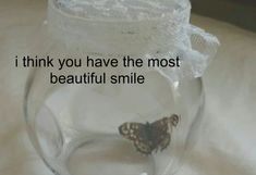 a butterfly sitting on top of a glass jar with the words i think you have the most beautiful smile