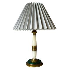 a table lamp with a white shade on the top and gold trimmings around the base