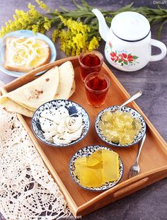 a tray with some food on it and two cups next to each other near a tea pot