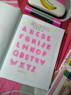 an open notebook with the letters and numbers written in neon pink on top of it