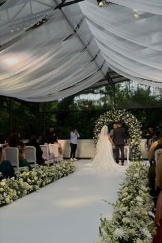 a bride and groom walking down the aisle in front of their guests at an outdoor wedding ceremony