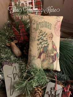 a christmas pillow sitting on top of a table next to pine cones and other decorations