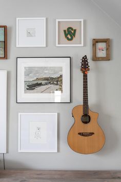 a guitar is hanging on the wall next to pictures