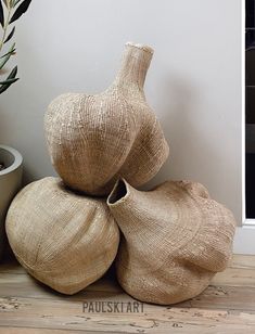 three burlap vases stacked on top of each other in front of a potted plant