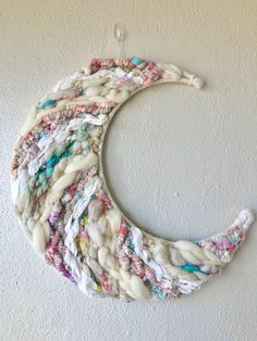 a circular piece of yarn hanging on the wall next to a white wall with a hook