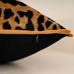 an animal print pillow is sitting on a white surface with black and yellow trimmings