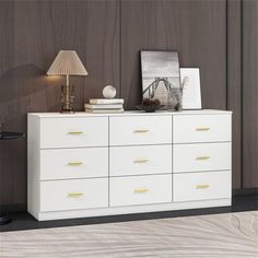 a white dresser sitting next to a lamp on top of a wooden floor in front of a wall